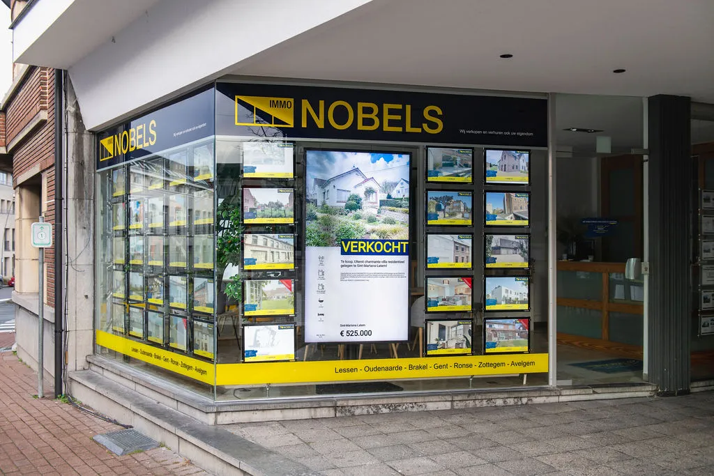 Het hoekkantoor van Immo Nobels met een scherm en verlichte panden in de etalage
