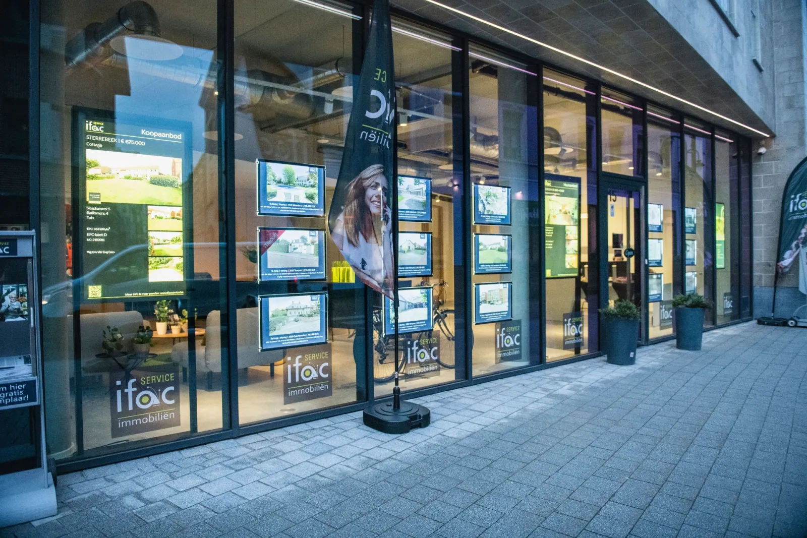 De etalage van Ifac Service met een scherm tussen de verlichte panden