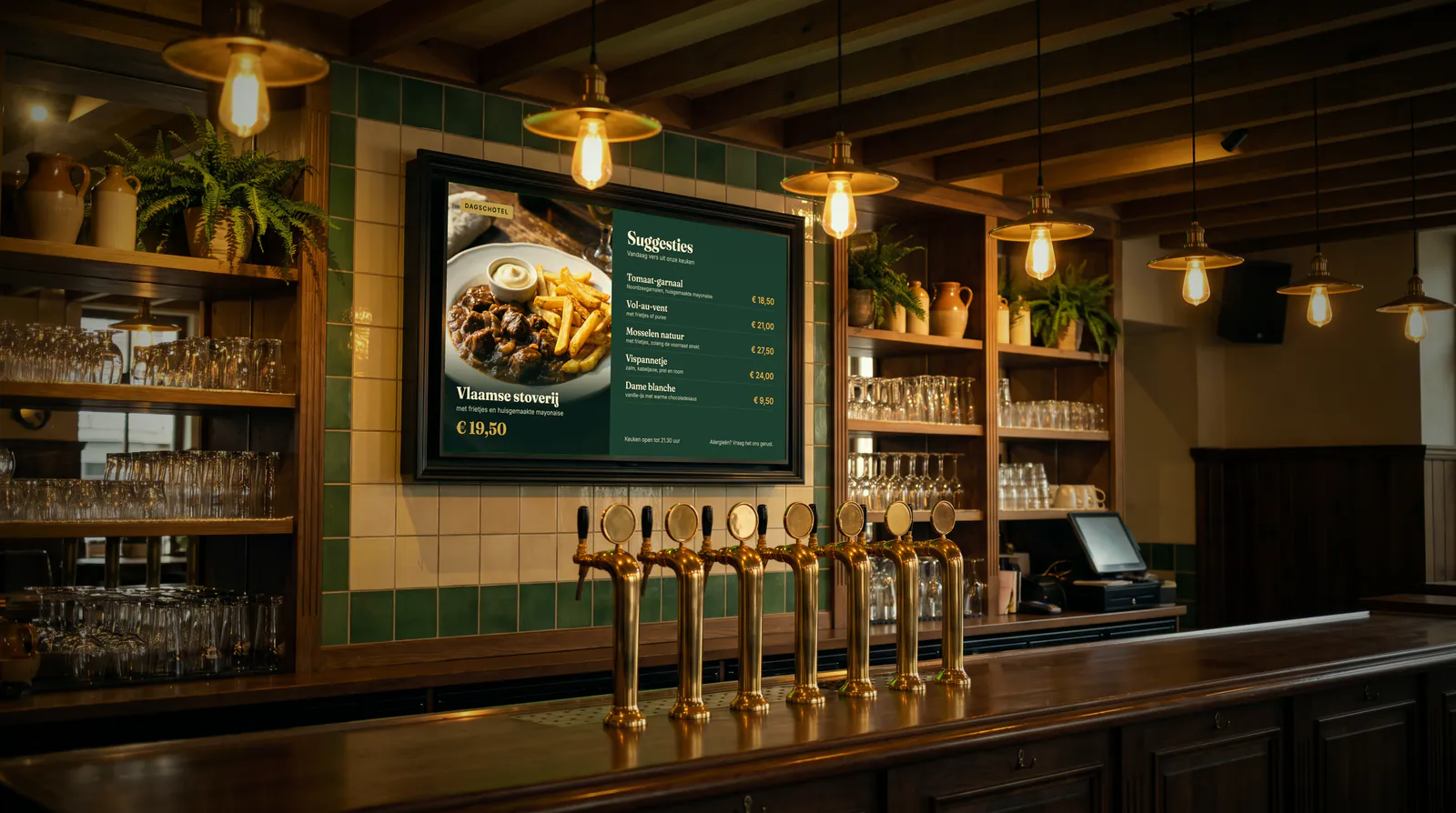 Toog van een brasserie met koperen tapkranen en een menubord tegen de groen betegelde muur