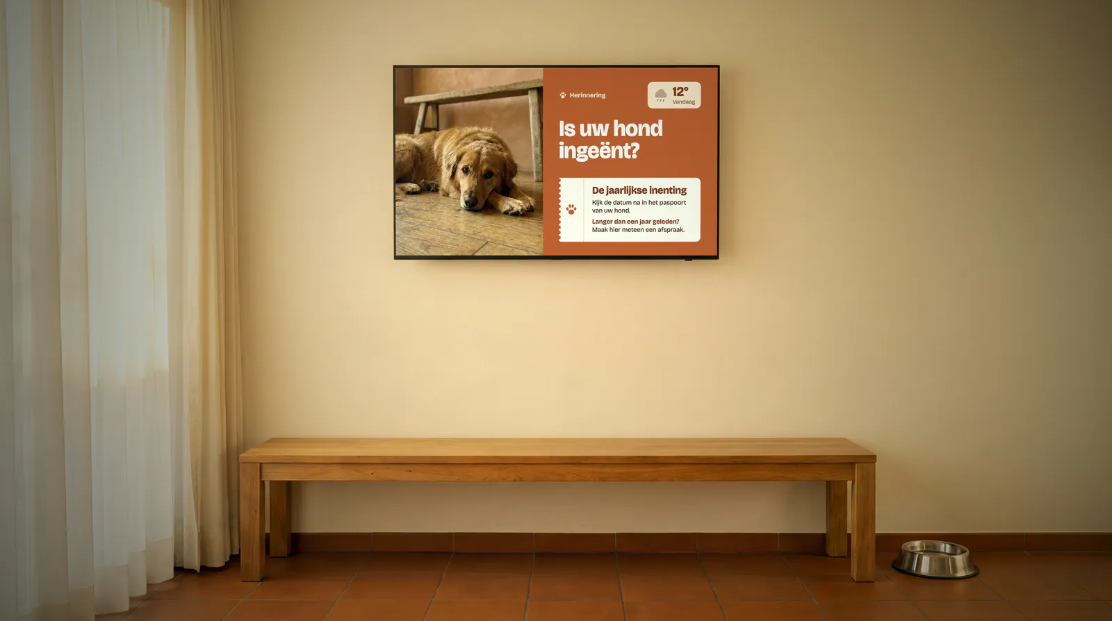 Wachtzaal van een dierenartspraktijk met een lange houten bank, een waterbak op de tegelvloer en een scherm met een hond en een herinnering aan de inenting